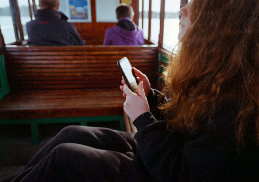 a woman sitting on a bench looking at a cell phone